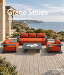 JANSSONG Grace outdoor sofa set with orange cushions and charcoal frames on a coastal terrace